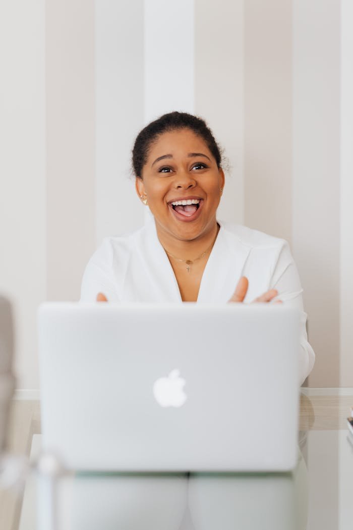 Happy black woman using a laptop at a modern office desk indoors.